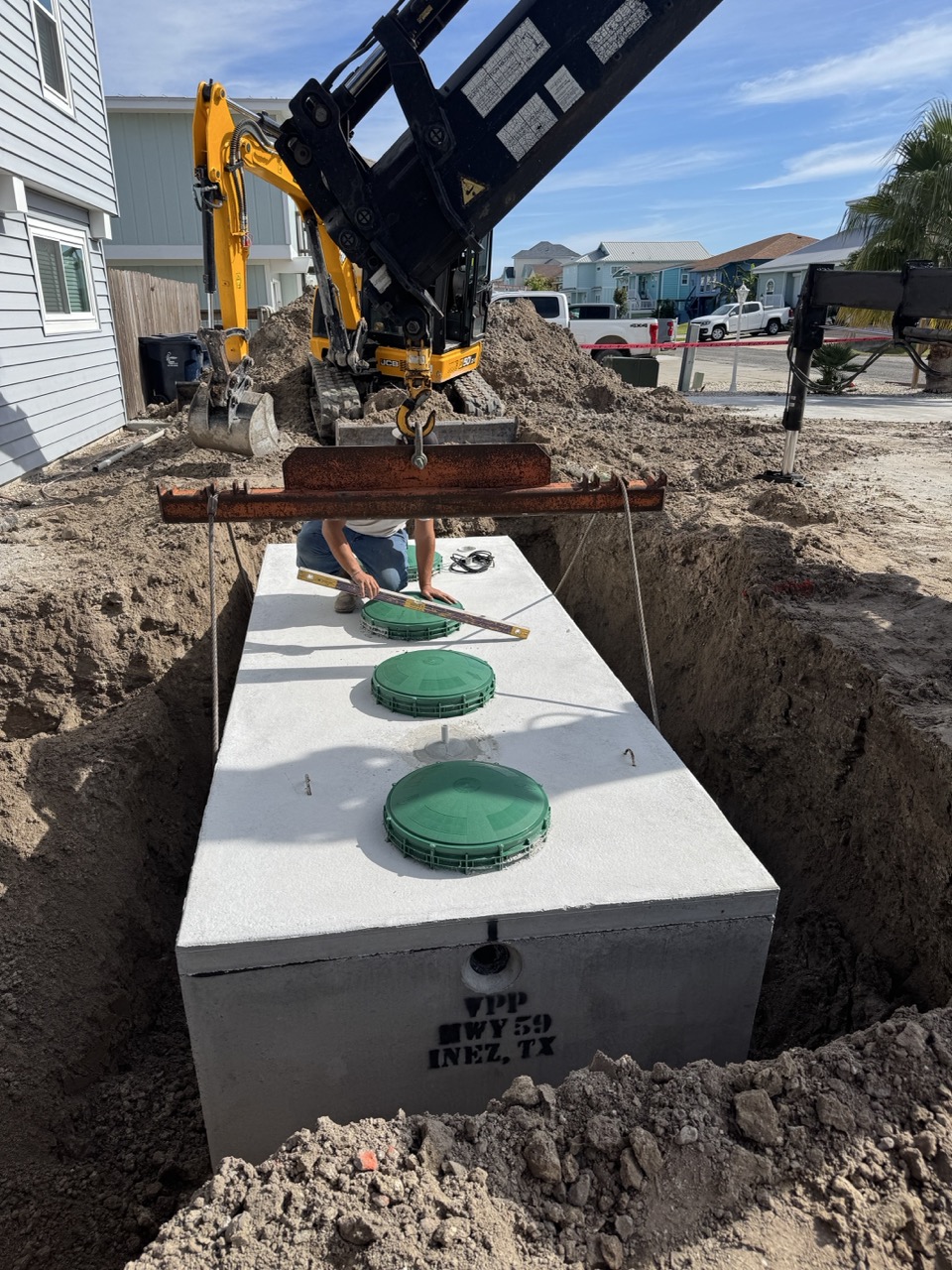 Technician leveling septic tank risers during an install